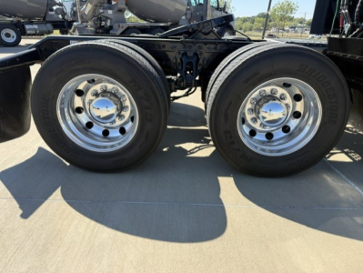Dual rear wheels on a Kenworth truck chassis showing chrome hubcaps and tires with Bridgestone branding.