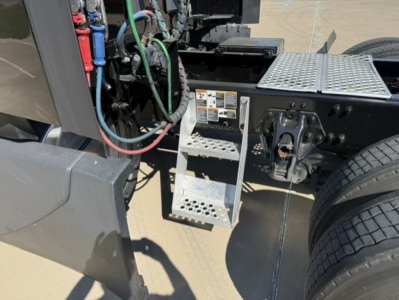 Kenworth T680 engine bay area showing access steps and chassis with wiring and connector harnesses.