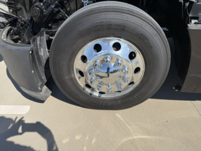 Kenworth T680 front wheel and hub area showing chrome lug nuts and tire.