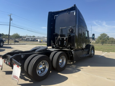 Kenworth T680 tractor rear-angled view showing dual rear axles and fifth wheel, black exterior, chrome wheels, cab with sleeper, side mirror, and rear lights.