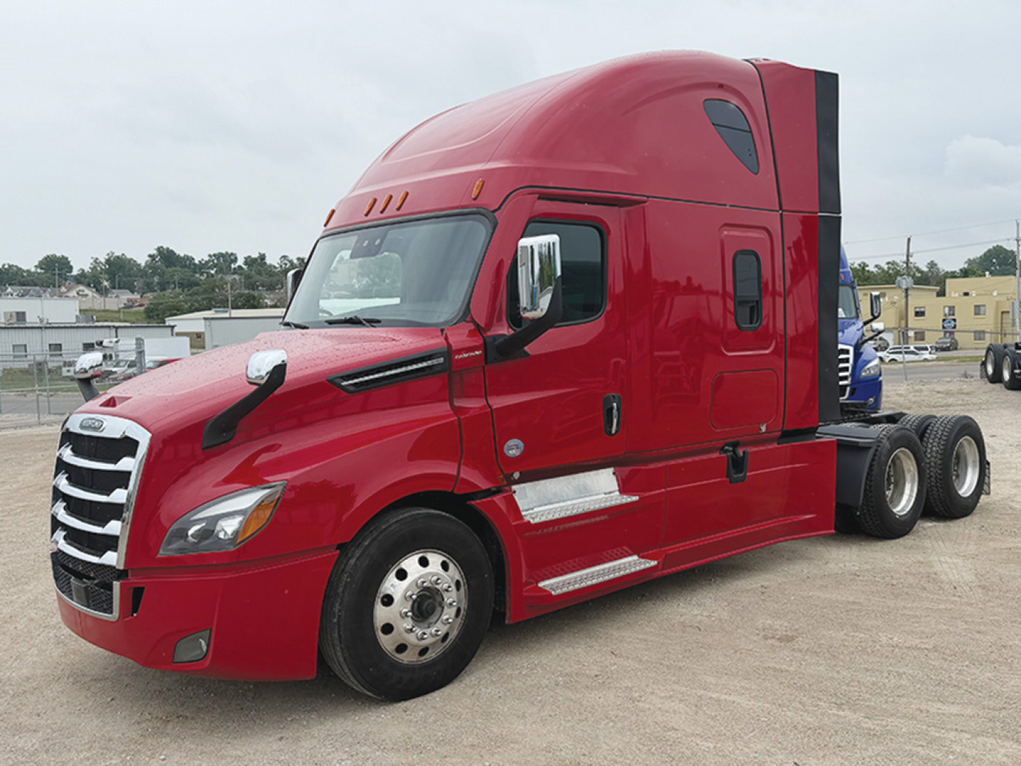 Red Freightliner Cascadia126 truck cab with sleeper, front three-quarter view showing chrome grille, headlights, side mirrors, door handles, and fuel/step areas.