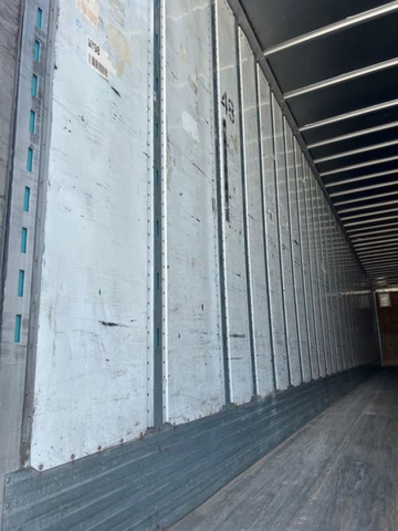 Trailer interior showing metal side walls and wooden floor of a used 2012 Utility Van trailer, long aisle with vertical steel ribs.