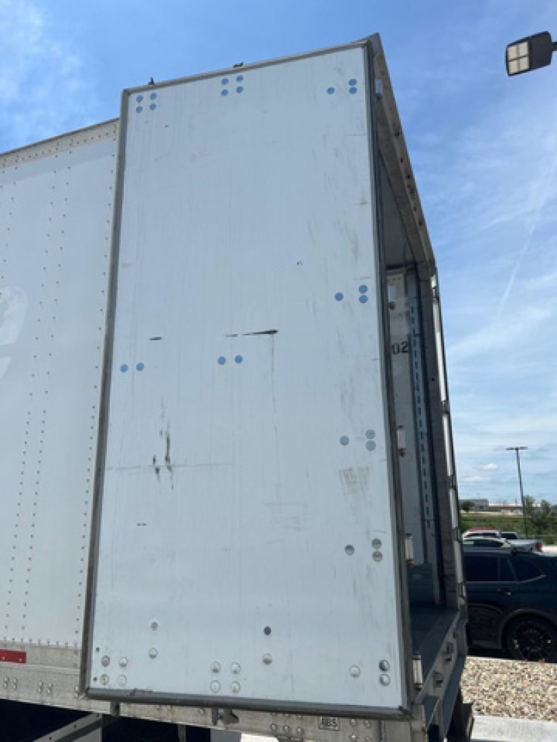 Trailer van side door open showing plain white metal exterior with rivets and hinges.