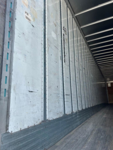 Trailer interior showing metal side walls and wooden floor of a used 2012 Utility Van trailer, long aisle with vertical steel ribs.