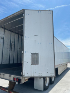 Trailer rear door open showing utility van trailer with metal exterior and rear underslung bumper lights.