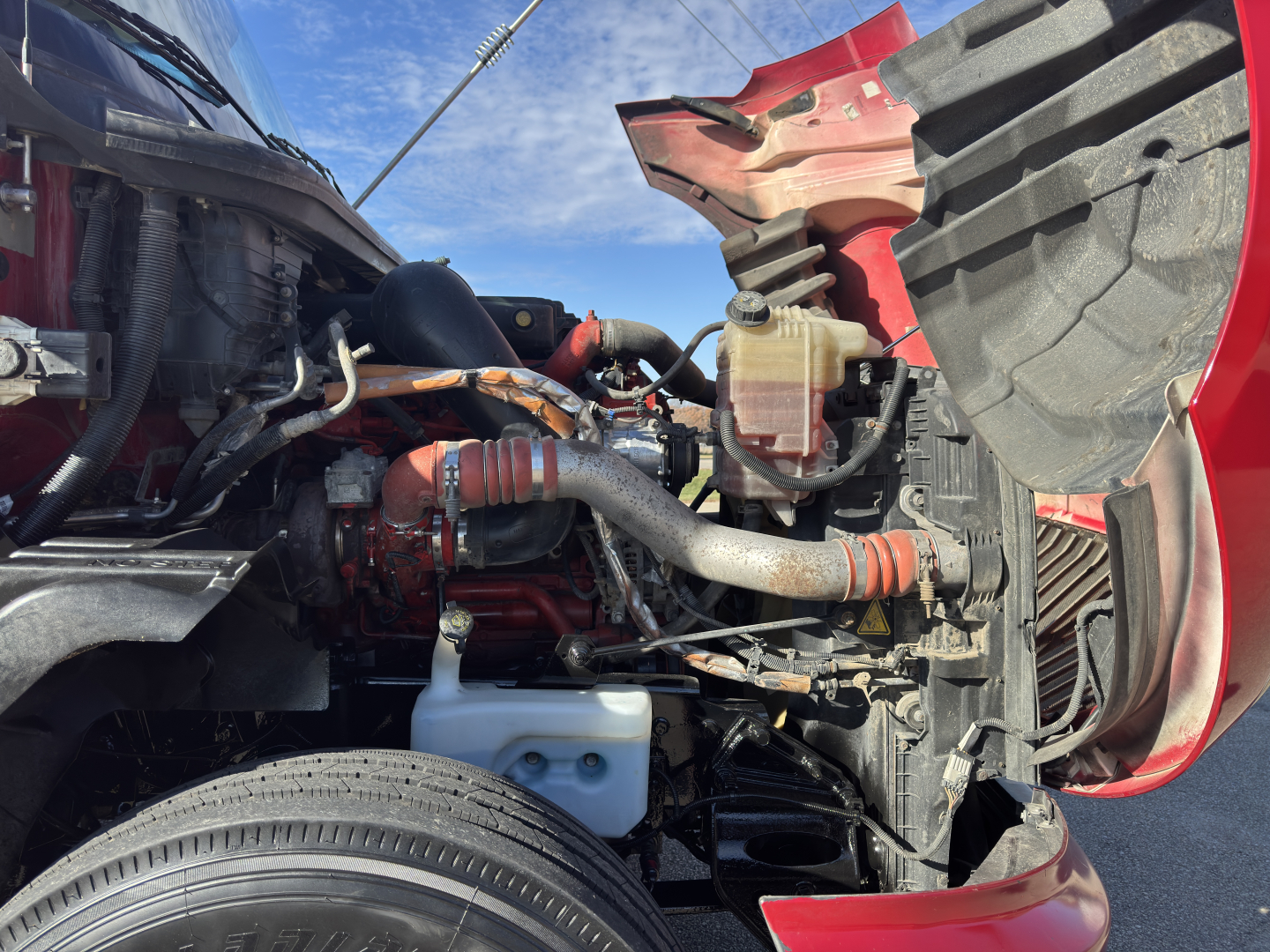 Truck engine bay of a 2018 International LT625 showing front section with radiator, hoses, reservoir, and engine components visible.