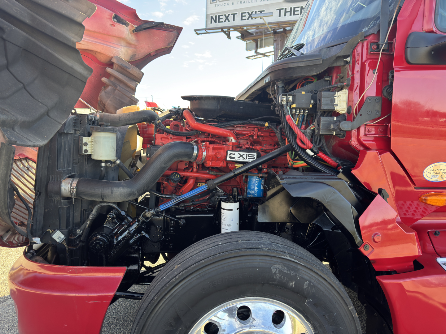 Truck engine bay with red LT625 diesel engine visible, hoses and components, hood open.
