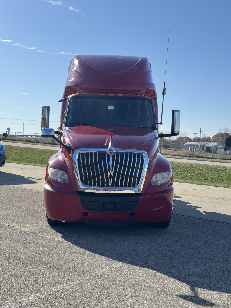 Truck front view of a burgundy 2018 International LT625 sleeper tractor, with large chrome grille, prominent hood, tall aerodynamic roof fairing, and side mirrors.