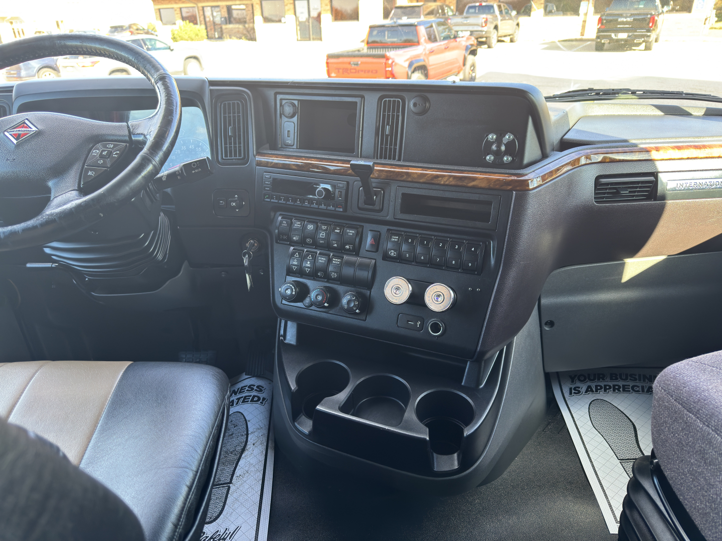 Interior view of a 2018 International LT625 driver cockpit showing dashboard with multiple gauges, center stack, steering wheel, and wood trim.