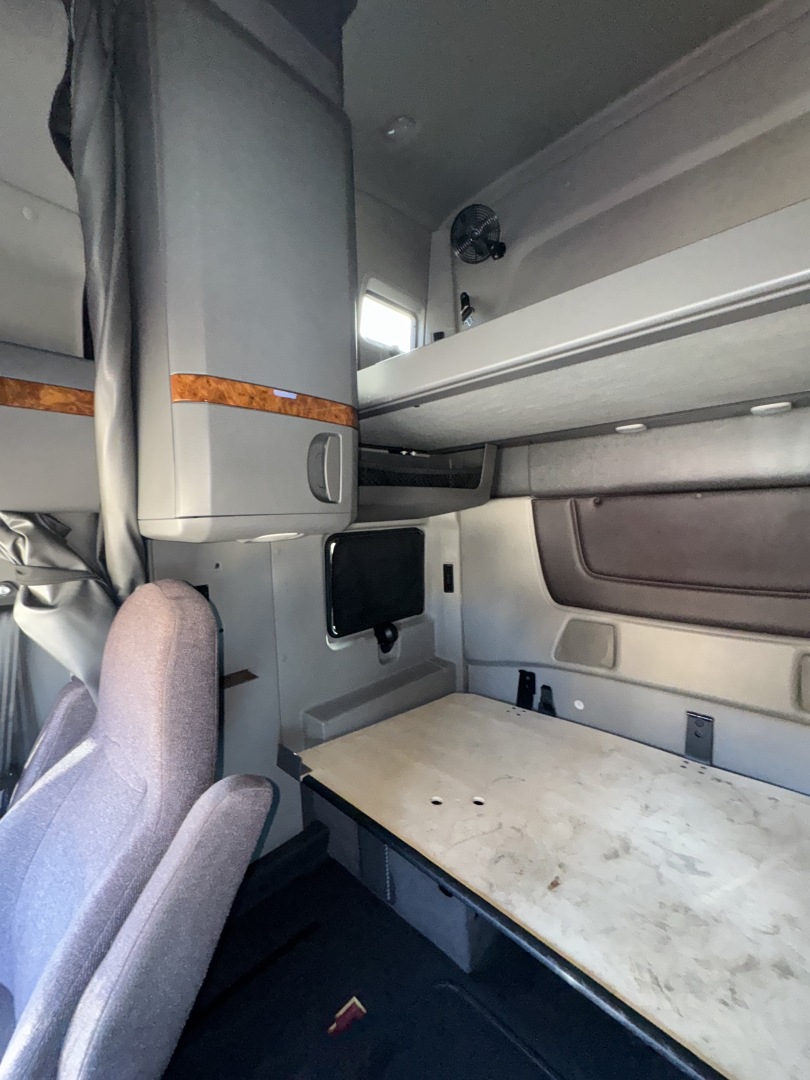 Interior sleeper cab of a 2018 International LT625 showing bunk area with table surface and storage cabinets.