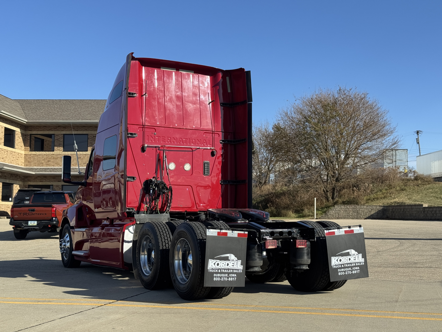 Truck cab rear view showing International LT625 emphasizes triple rear axles and pink/red cab with black mud flaps
