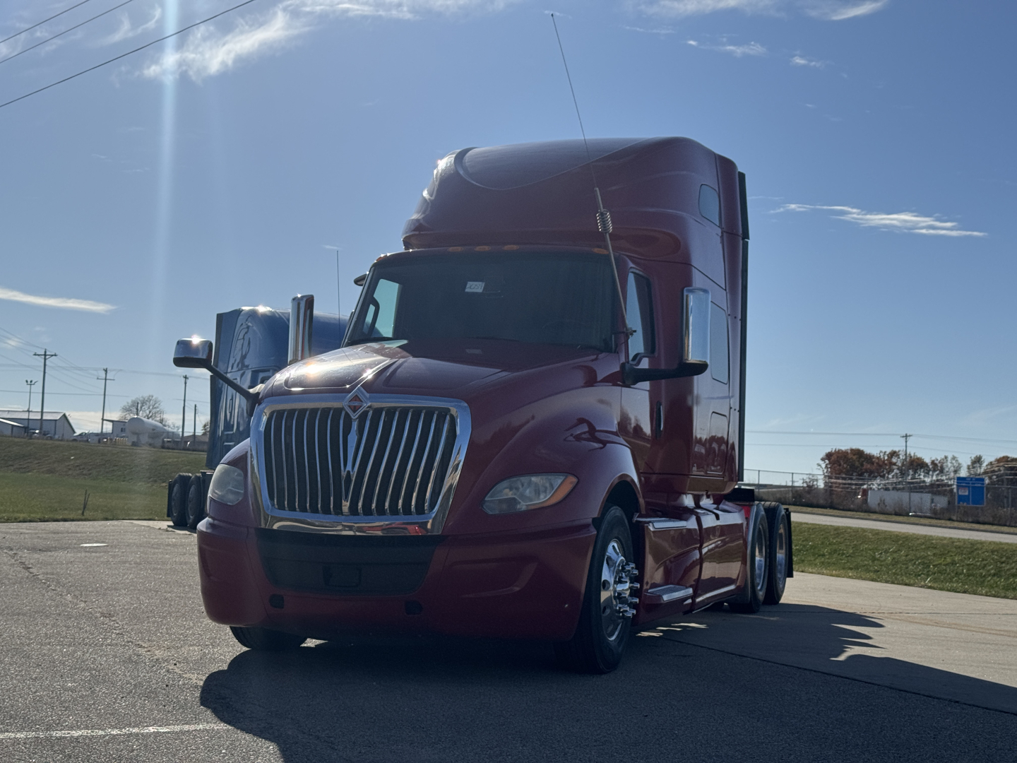 2018 International LT625 semi-truck in a parking lot, maroon cab with chrome grille, dual rear wheels, side mirrors, daytime sky.