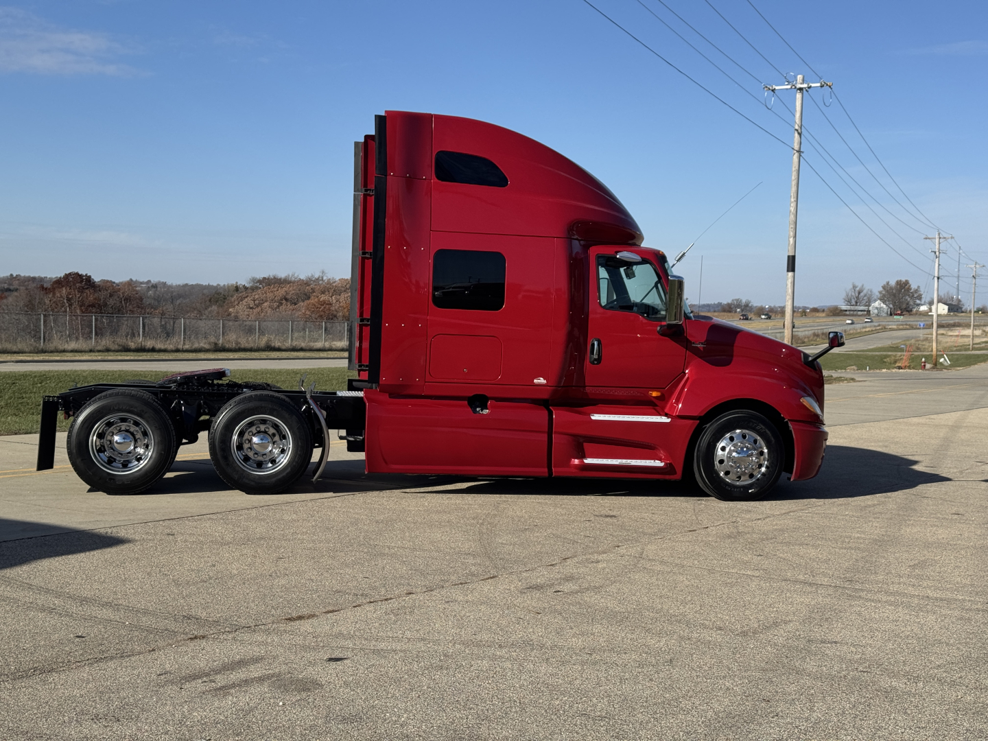Truck cab side view of a red 2018 International LT625 conventional sleeper tractor with triple rear axles and chrome wheels.