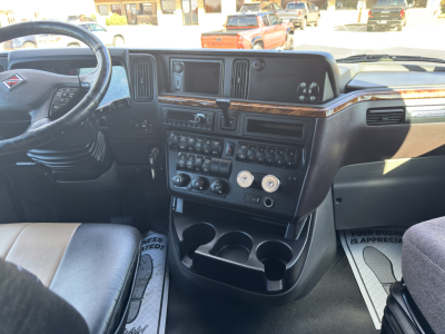 Interior view of a 2018 International LT625 driver cockpit showing dashboard with multiple gauges, center stack, steering wheel, and wood trim.