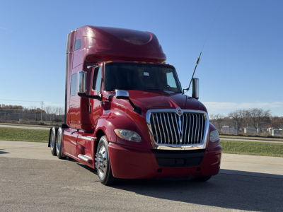 Truck front view showing International LT625 sleeper cab, red exterior, chrome grille, headlights, and side mirrors.
