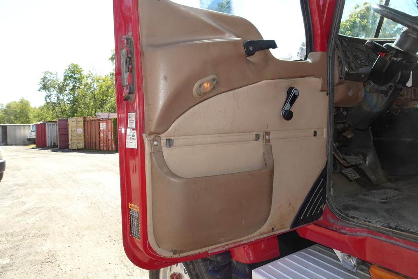 Truck cab interior door panel and open door from a 2005 Mack CV Granite CV713 showing brown door panel and control handles.