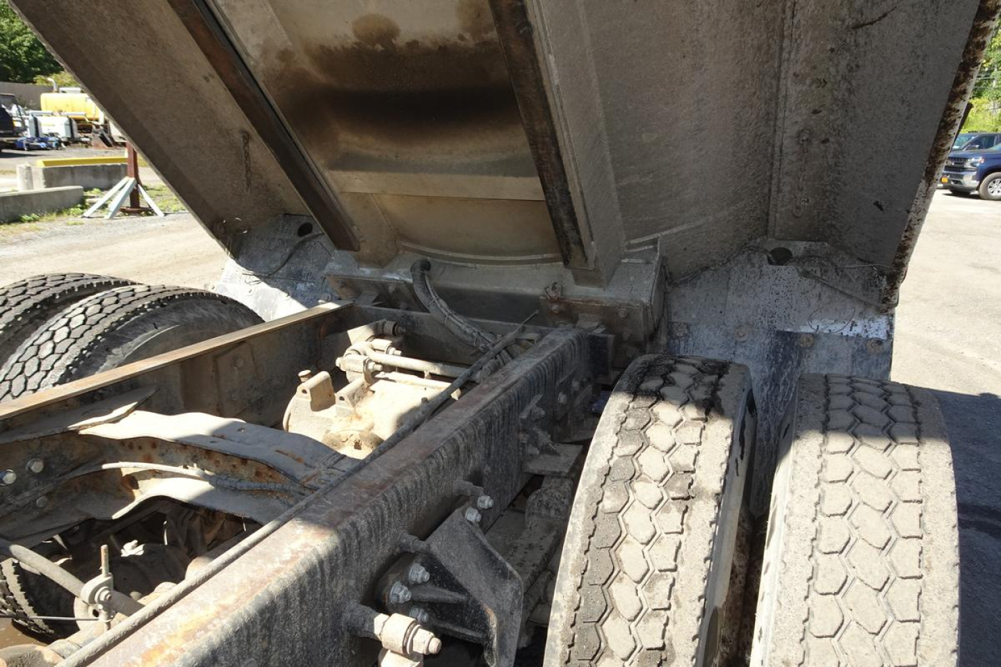 CV-style truck undercarriage showing dual rear wheels and dumping bed hinge with hydraulic components.