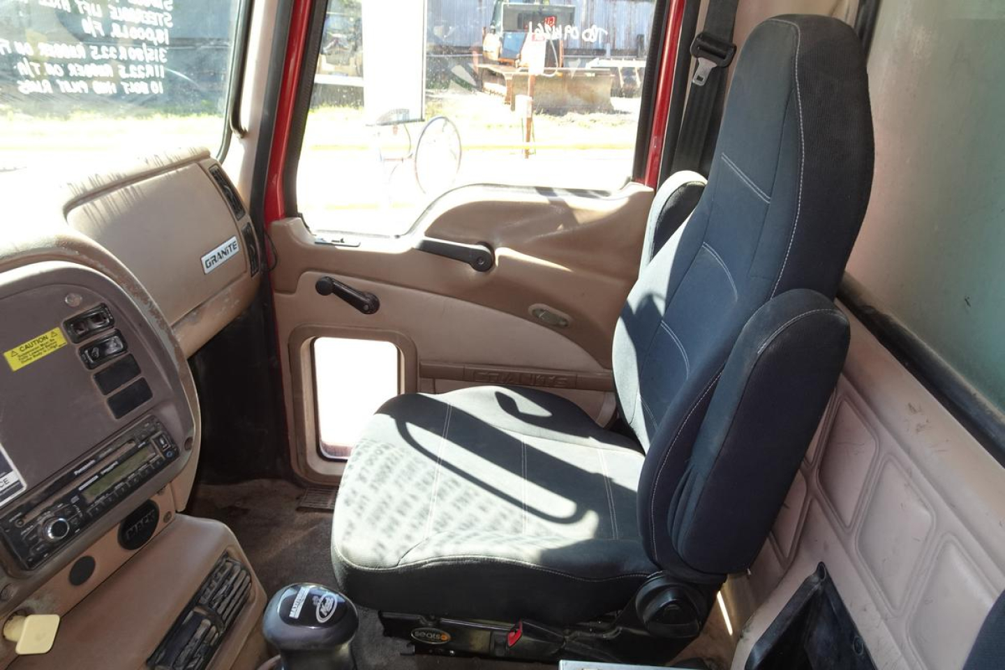 Cab interior of a Mack CV (Granite) CV713 truck showing driver seat, steering wheel, and dashboard area.