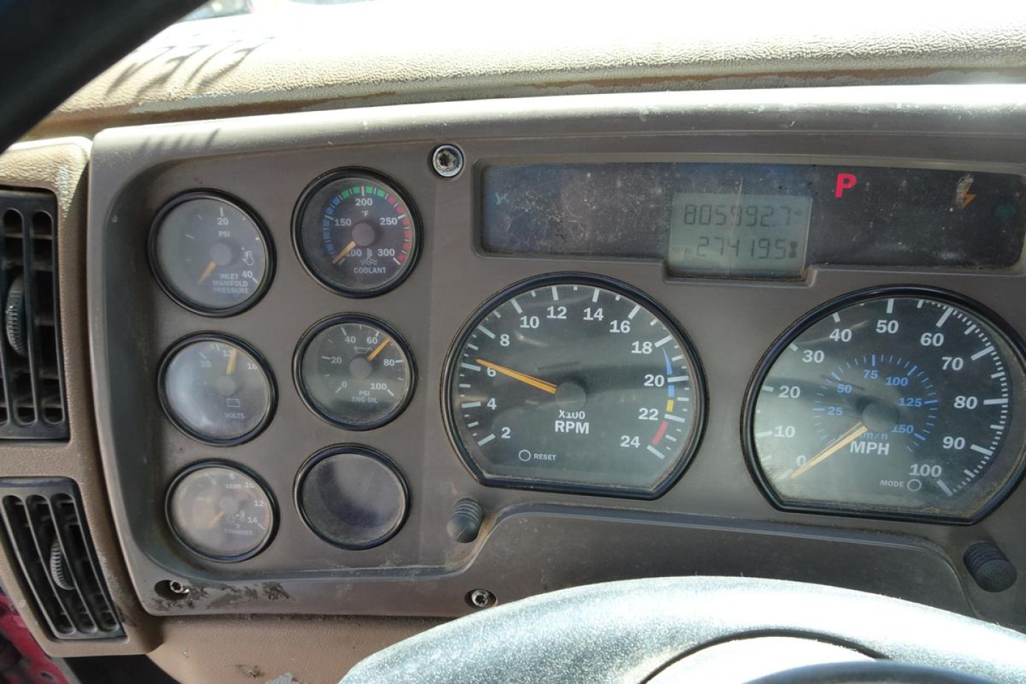 Mack CV (Granite) truck dashboard showing gauges and digital odometer reading; multiple circular meters and a large central tachometer.