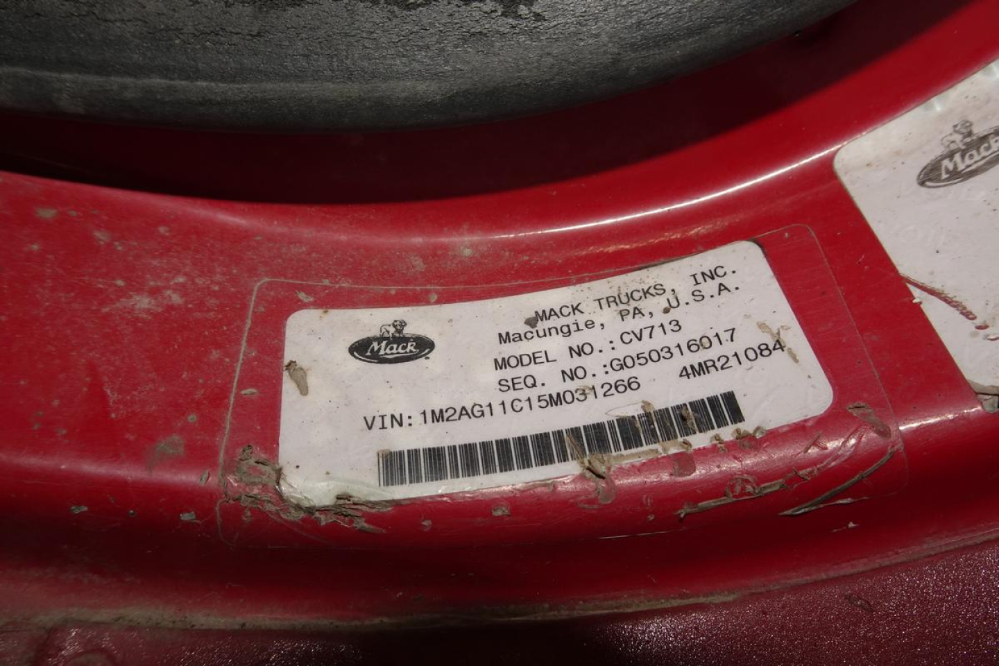 Label on Mack CV713 truck showing VIN, model, and stock information. Readable text includes: MACK TRUCKS INC., Macung, DN, USA? MODEL NO. CV713, VIN: 1M2AG11C15M031266, SEQ. NO.: 603041R? - unclear. Location sticker with bar code.