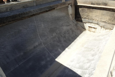Inside of dump truck bed showing smooth metal surface with worn edges and channels. No identifiable text visible.