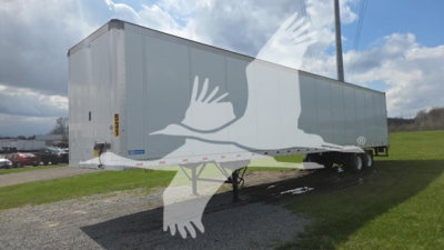 Stoughton plate van trailer side view showing a long rectangular cargo box on dual rear axles, with a front cab area not visible, and a gravel lot background.