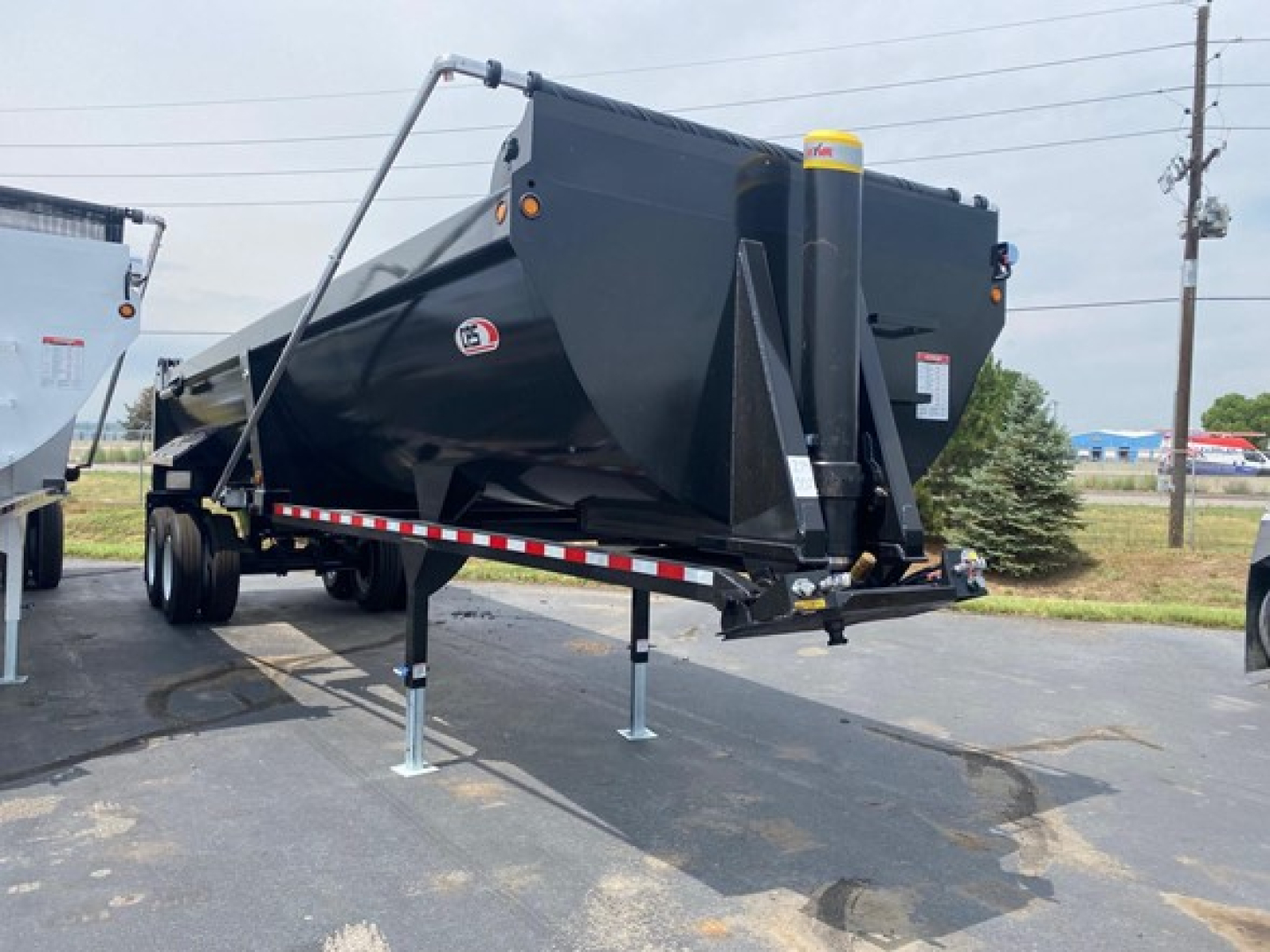 CPS 34' frameless steel rock end dump trailer in new condition, black finish, with hydraulic ram and support legs visible; front end shows hitch and yellow warning cap; VIN 150118606020, Stock NE8549.
