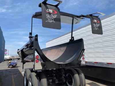 CPS 34' frameless steel rock end dump trailer viewed from rear-left, with dual wheels, hydraulic hoist, CPS branding on banners, and reflective taillights.