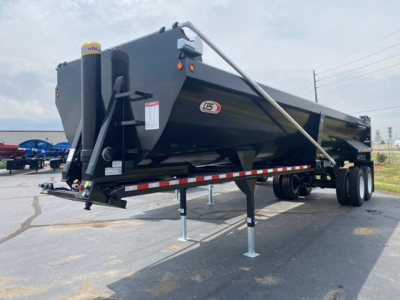 Rock end dump trailer showing LPX logo and side-mounted hydraulic components with a raised chassis and support legs.