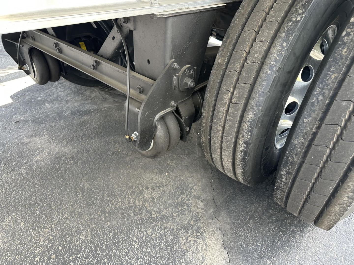 Trailer wheel assembly and landing gear visible with dual rear axles and suspension components.