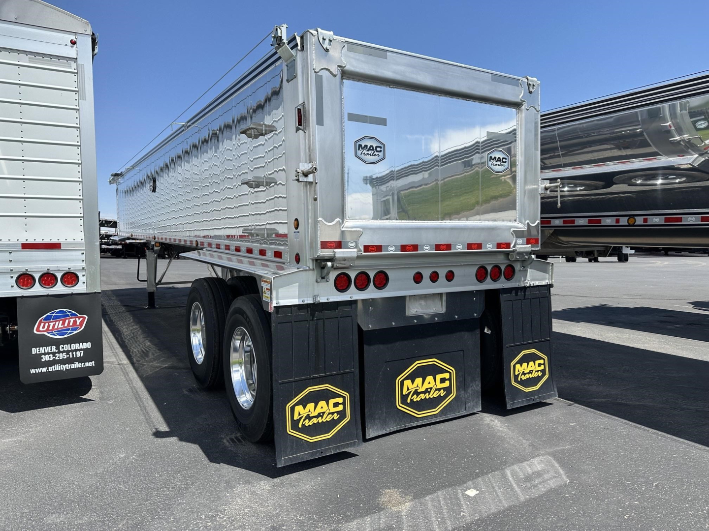 Mac lightweight frameless aluminum end dump trailer showing rear view with MAC mud flaps and dual wheels, metal tailgate, and reflective tape.