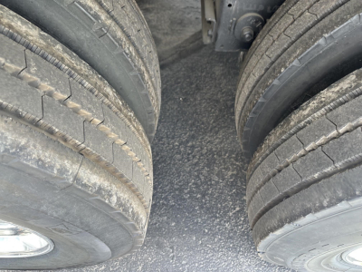 Dual rear axles on a frameless aluminum end dump trailer showing heavy-duty tires and deck surface.