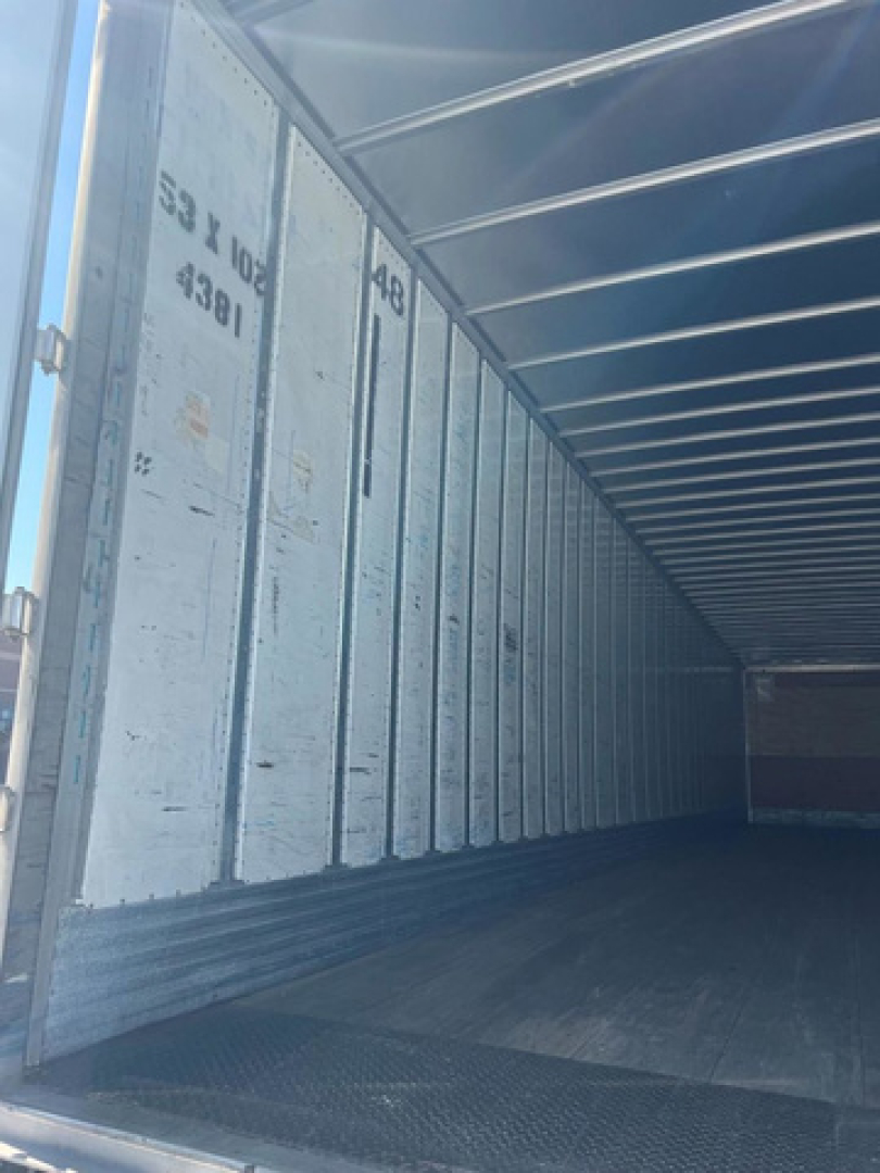 Trailer interior showing metal walls with vertical ribs and stamped markings: '53 x 102' '4391' and other numbers on the side panels.