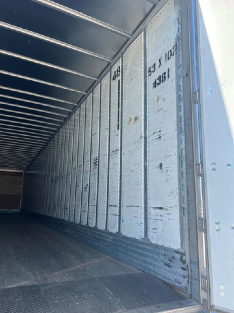 Trailer interior showing ribbed metal walls with weight and dimension markings along the side.