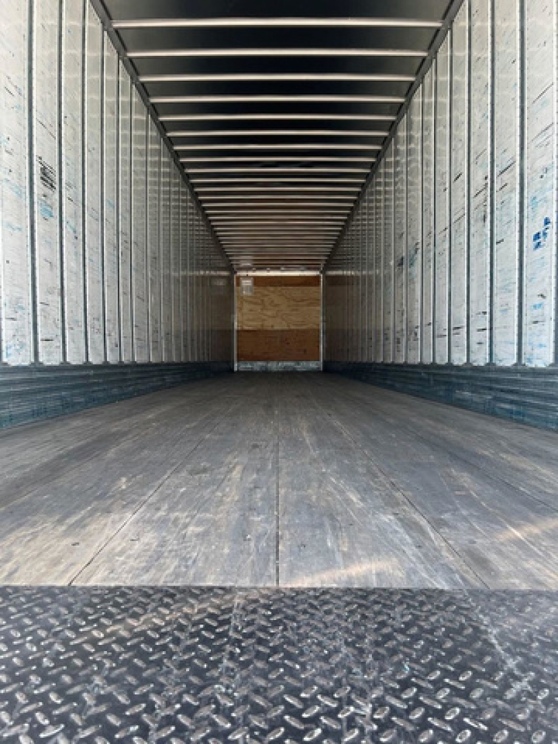 Utility van trailer interior showing empty cargo space with metal side walls and wooden floor.