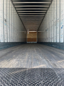 Utility van trailer interior showing empty cargo space with metal side walls and wooden floor.