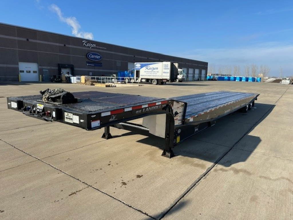 Landoll 440 equipment trailer in a dealership lot showing a long flatbed with ramp sections and branding stickers along the side.