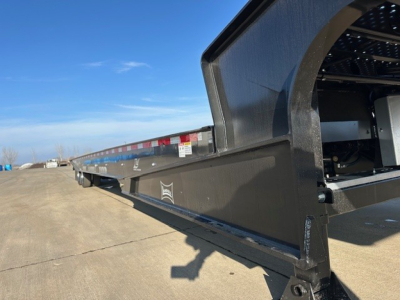 Landoll 440 trailer side view showing long flatbed with black metal frame and blue sky background.