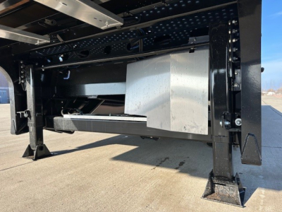 Underframe of a Landoll trailer showing structural beams, black-painted steel, and a large metallic box/drawer assembly inside the frame.