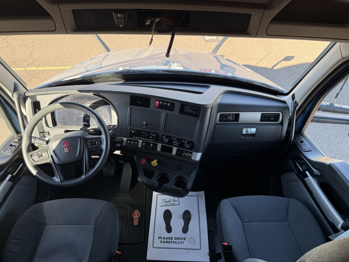 Kenworth T680 interior dashboard and steering wheel view from the driver seat, with center console, gauges, and pedals visible