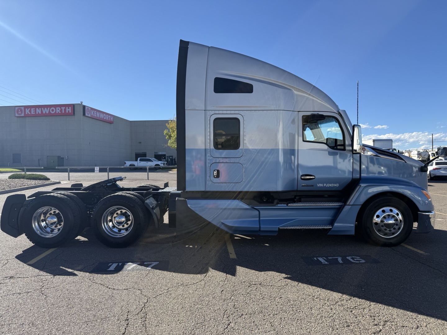 Kenworth T680 side view showing sleeper cab and dual rear axles in a parking lot.
