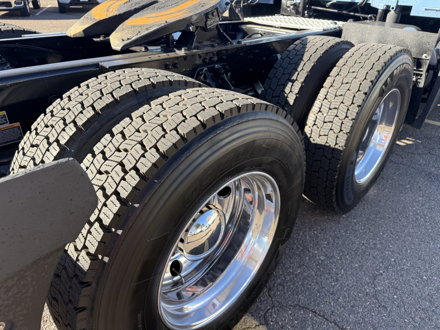 Kenworth T680 truck rear wheels and dual tires on trailer chassis, chrome rims, tread patterns visible.