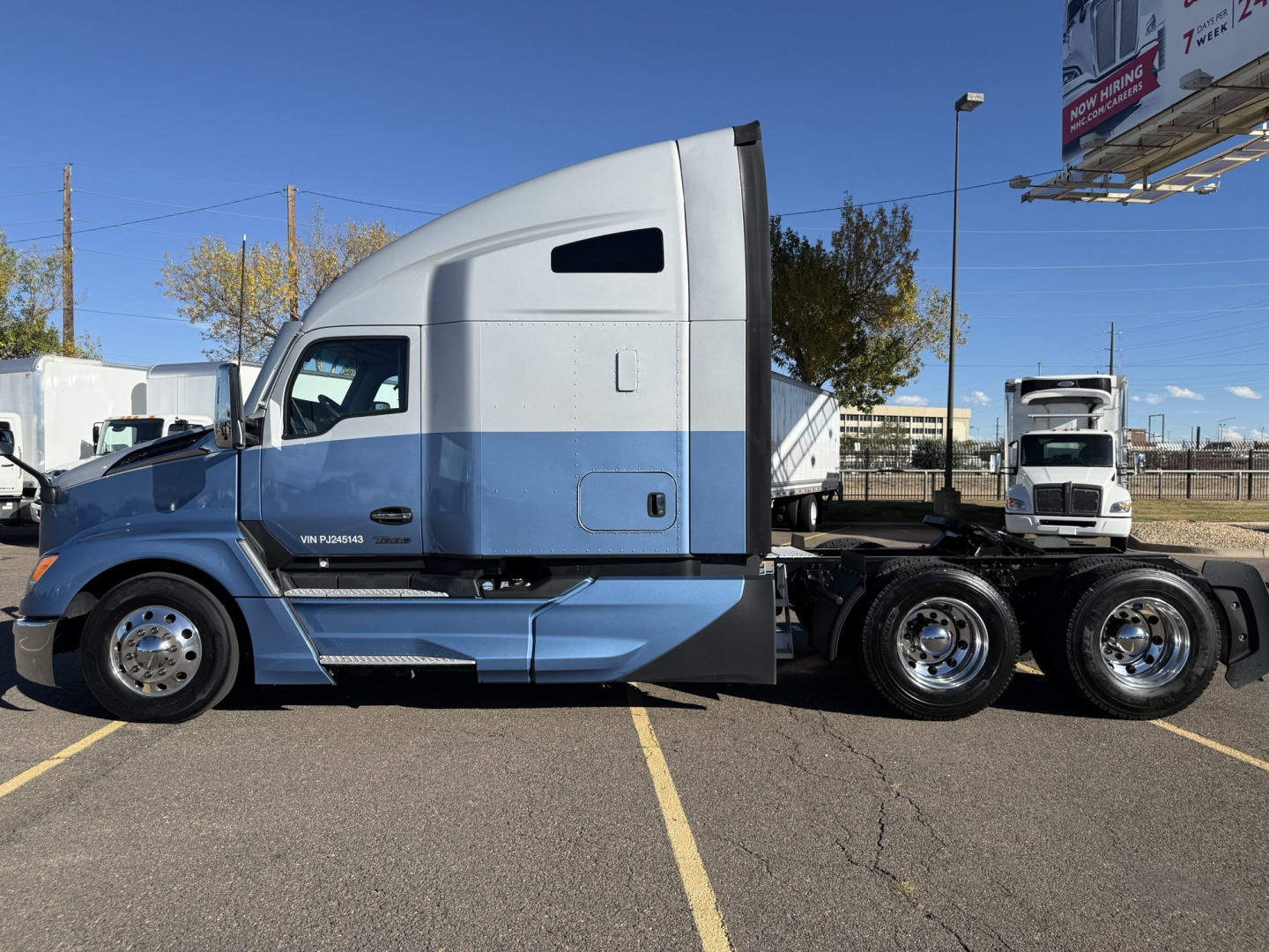 Kenworth T680 semi truck side profile showing sleeper cab and dual rear axles, blue and silver exterior, VIN and stock info not visible on image.