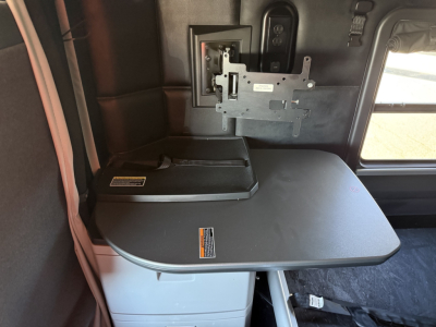 Interior of Kenworth T680 cab showing fold-out table with mounted bracket and window in view.