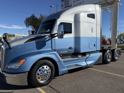 Kenworth T680 tractor with light blue and white cab in-service, side view showing fuel tanks and chrome wheel, VIN 1XKYD49X7PJ245143 plate-like sticker on door.