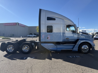 Kenworth T680 side view showing sleeper cab and dual rear axles in a parking lot.