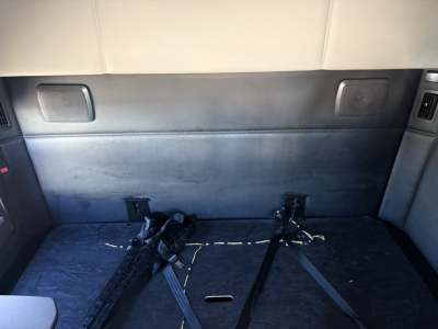 Rear cargo area of a 2023 Kenworth T680 sleeper cab showing a flat floor with seat belt straps and latches.