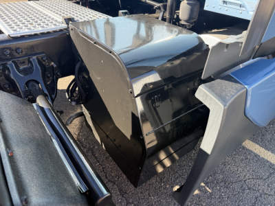Kenworth T680 truck cab area showing a glossy black toolbox or fender enclosure under the sleeper with metal step and chassis visible