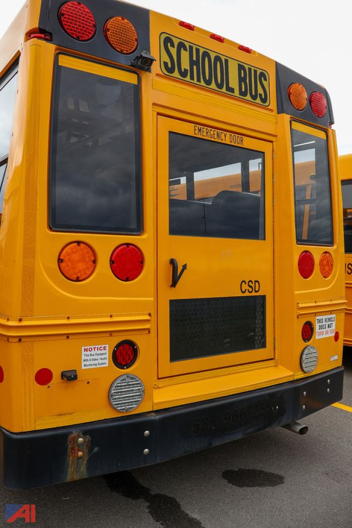 Rear view of a yellow Ford Blue Bird school bus with SCHOOL BUS signage, emergency door, lights, and reflective panels.