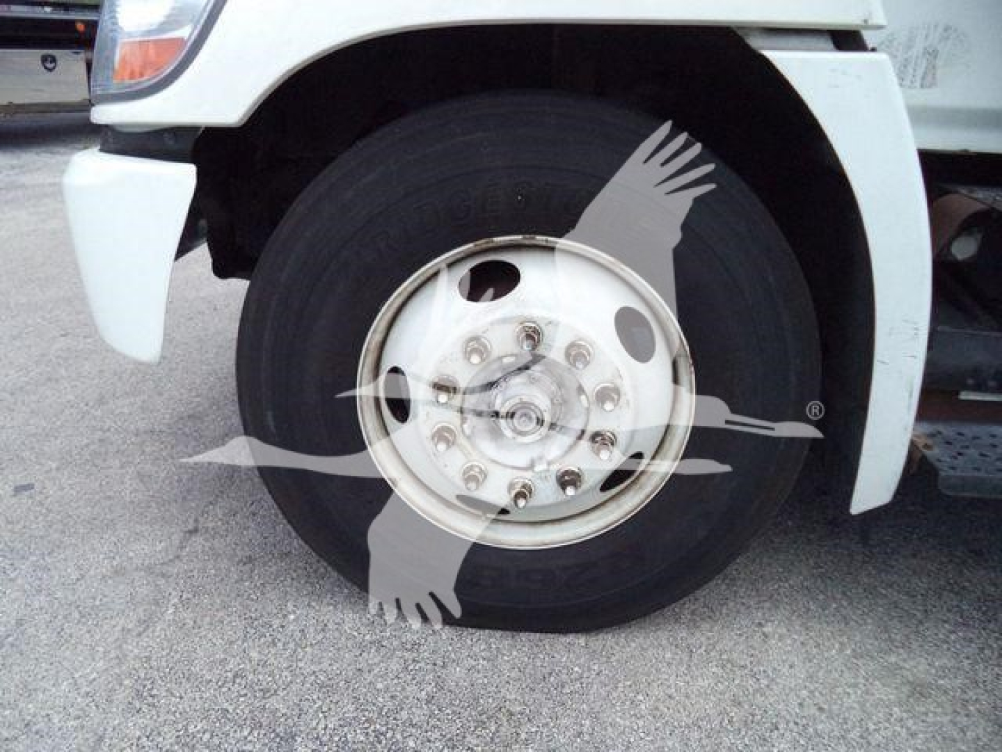 Front wheel and tire of a 2019 Hino 268A refrigerated truck showing front fender and wheel hub with lug nuts.